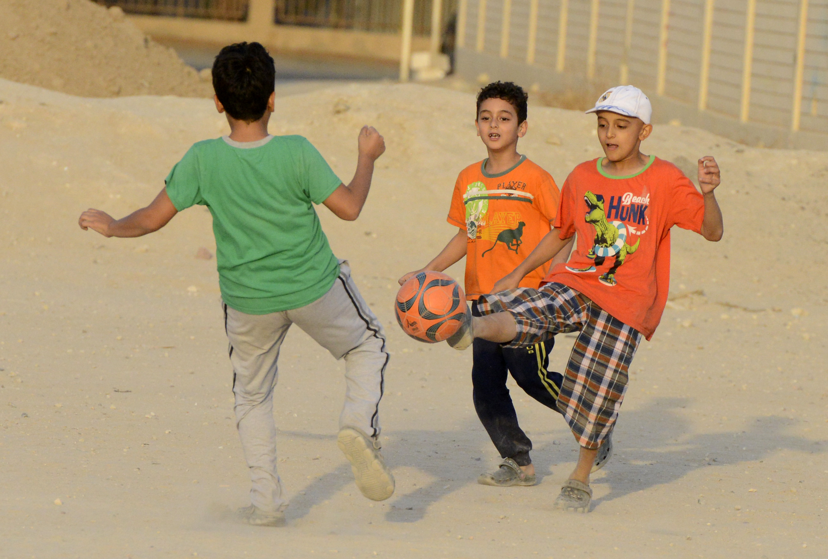 A group of children playing football in dirt pitches