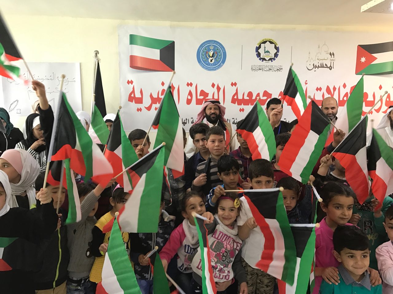 مجموعة من الأطفال يحملون اعلام الكويت خلال الحملة الإنسانية