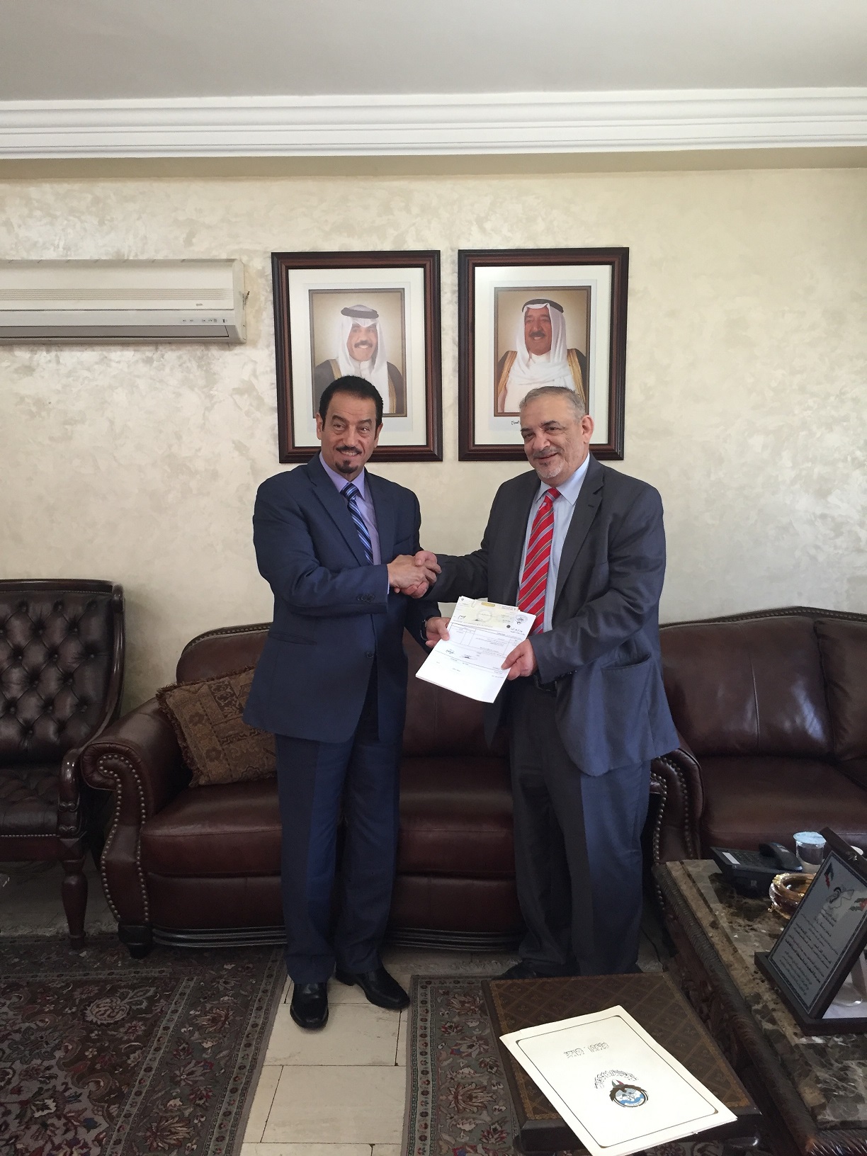 Kuwait's ambassador to Amman Dr. Hamad Al-Duaij handing the monetary sum, given by Kuwait's Zakat House