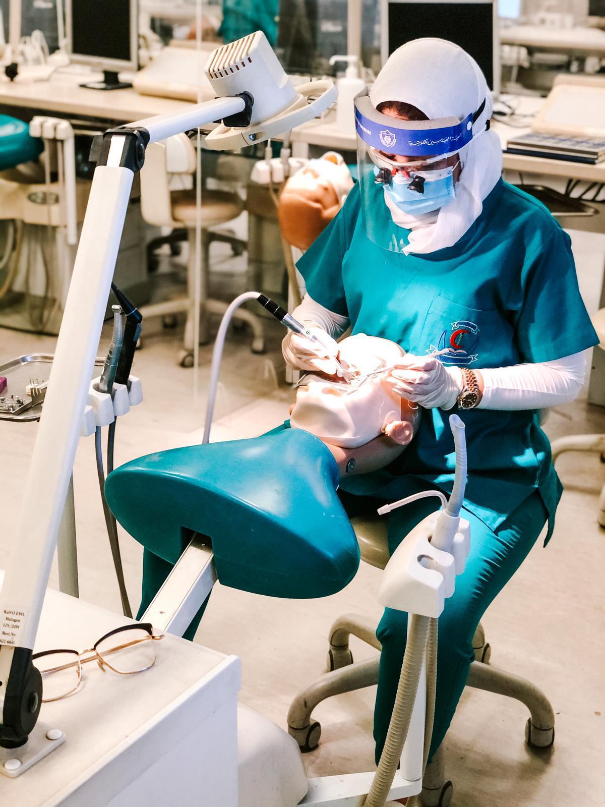 احدى طالبات كلية طب الاسنان تمارس تدريب عملي في المختبرات الطبية التخصصية