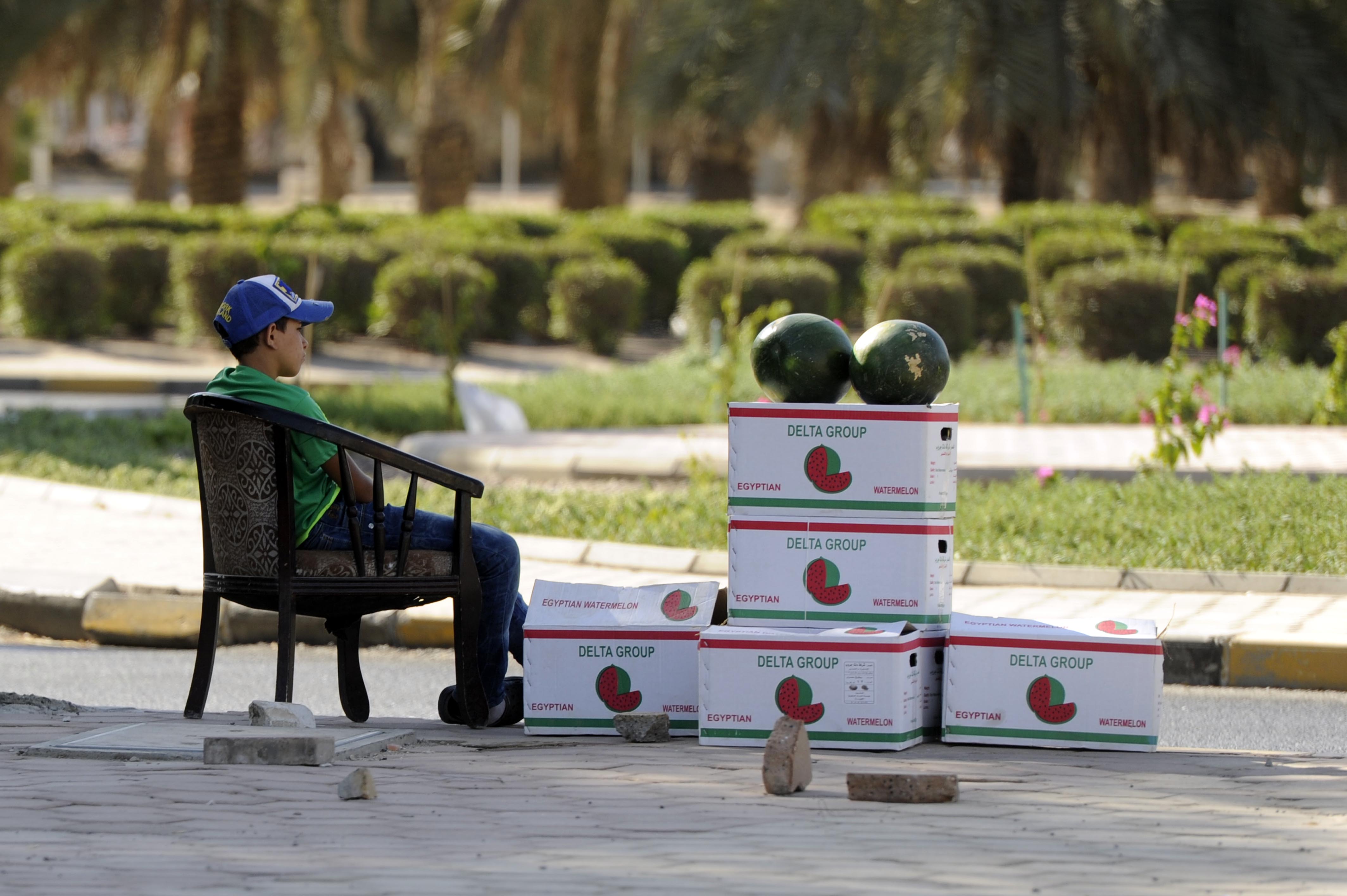 A child is waiting for customers to buy watermelons in the hot weather