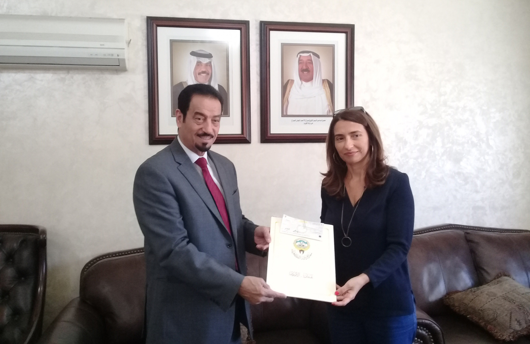 Kuwait's Ambassador to Jordan Dr. Hamad Al-Duaij hands the donation to the consultant to UNRWA's Director General Maria Mohammadi