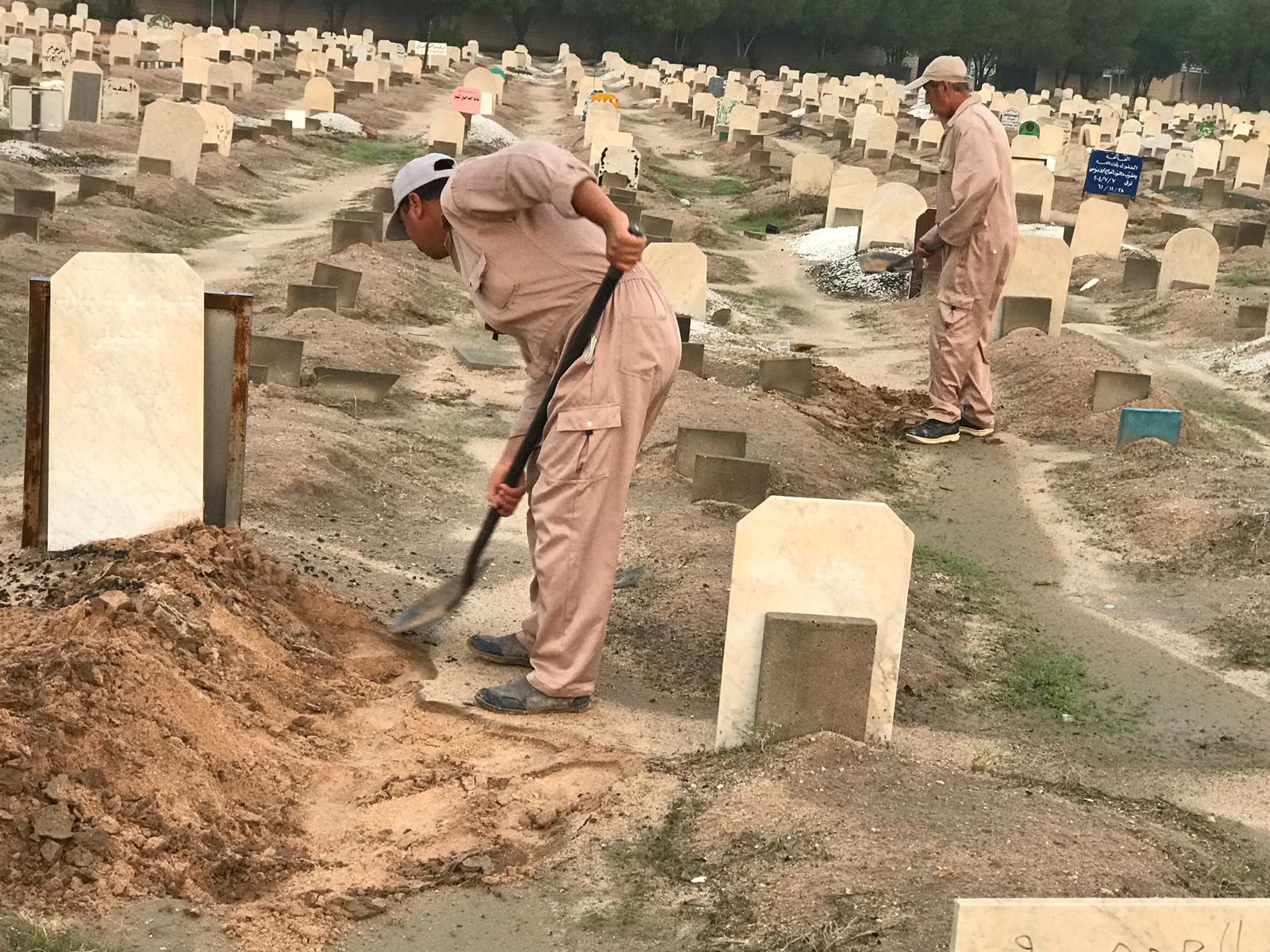 عمال في إدارة شؤون الجنائز ببلدية الكويت خلال القيام بإصلاح القبور الهابطة من جراء الأمطار الغزيرة