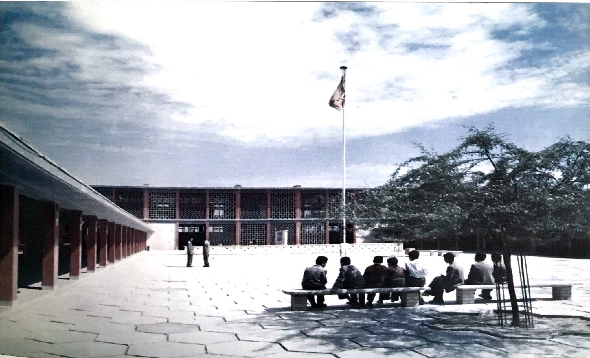 ساحة مدرسة ابتدائية ويظهر العلم القديم والممرات المكسوة بالقواطع المشبكة