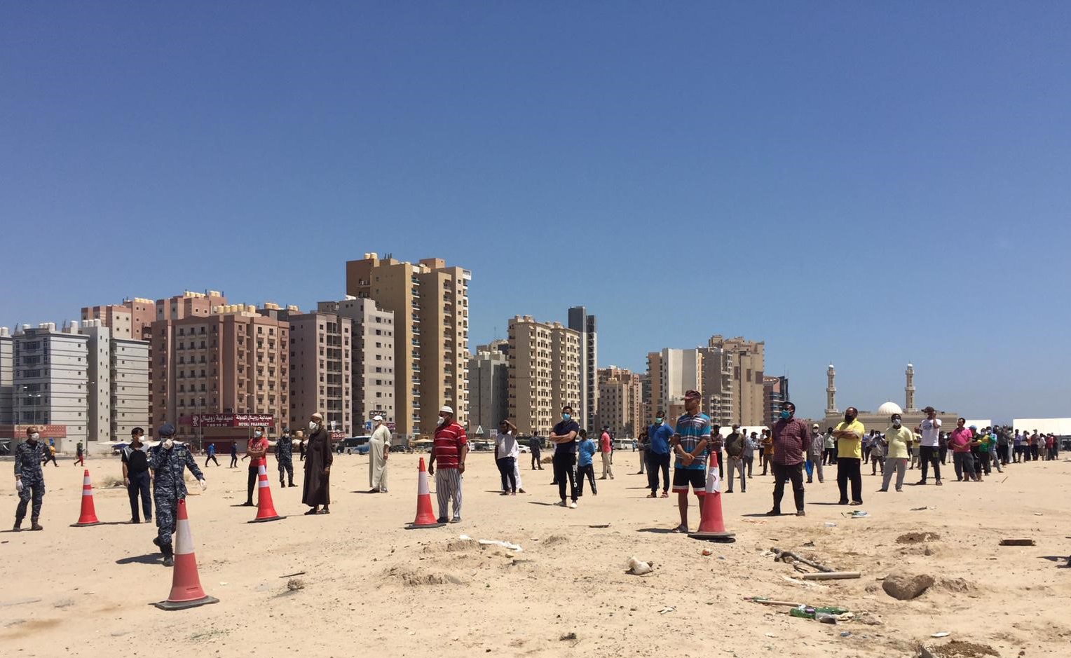 Workers in Al-Mahboula area line up to receive the baskets