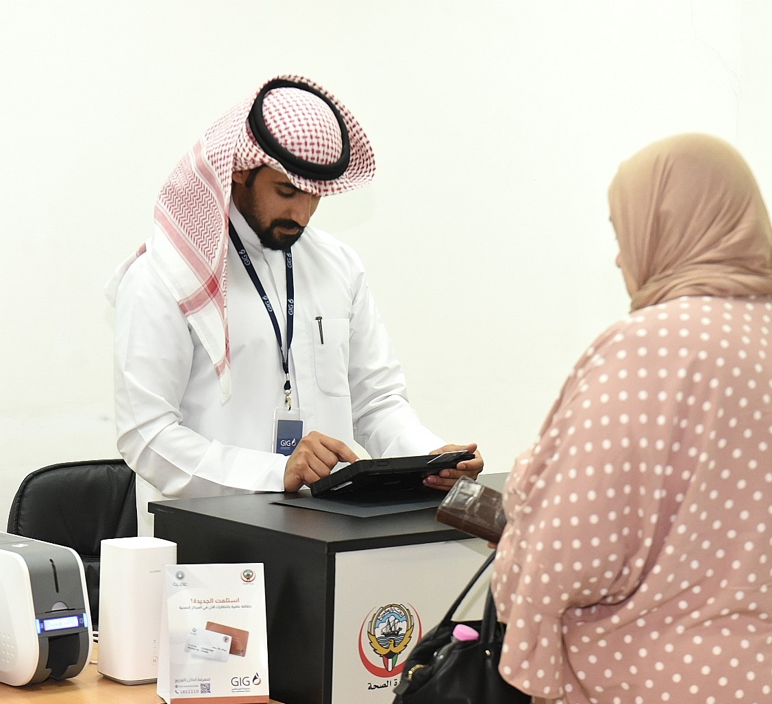 A retired Kuwaiti woman receiving her Afya-3 health insurance card