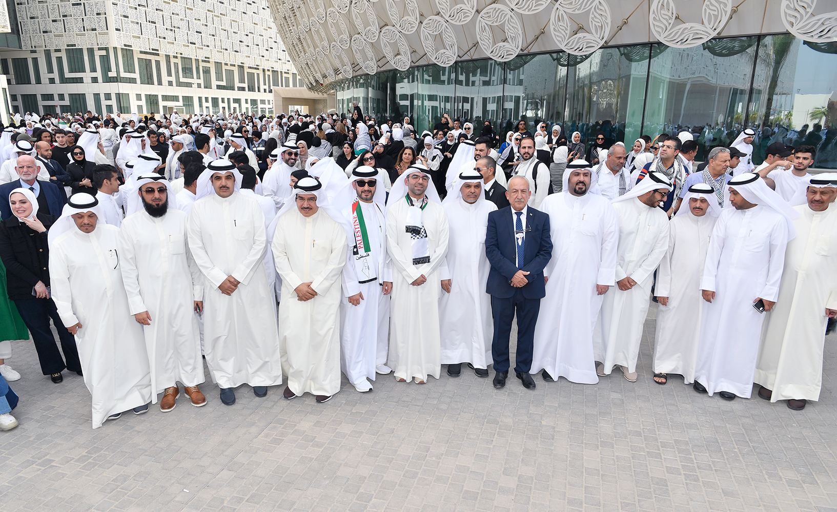 A group photo of Kuwait University officials and professors standing by Palestinians
