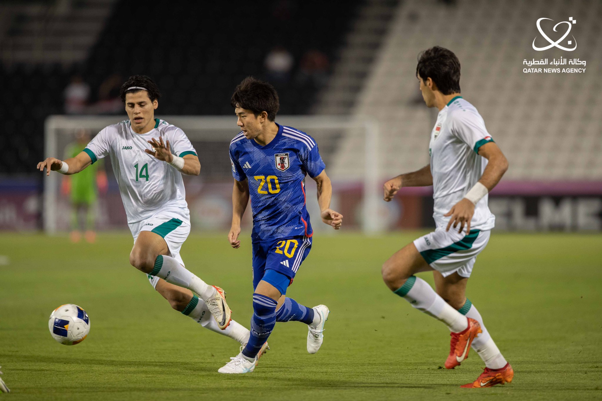 لاعب اليابان يمرر الكرة رغم محاصرة لاعبي العراق له