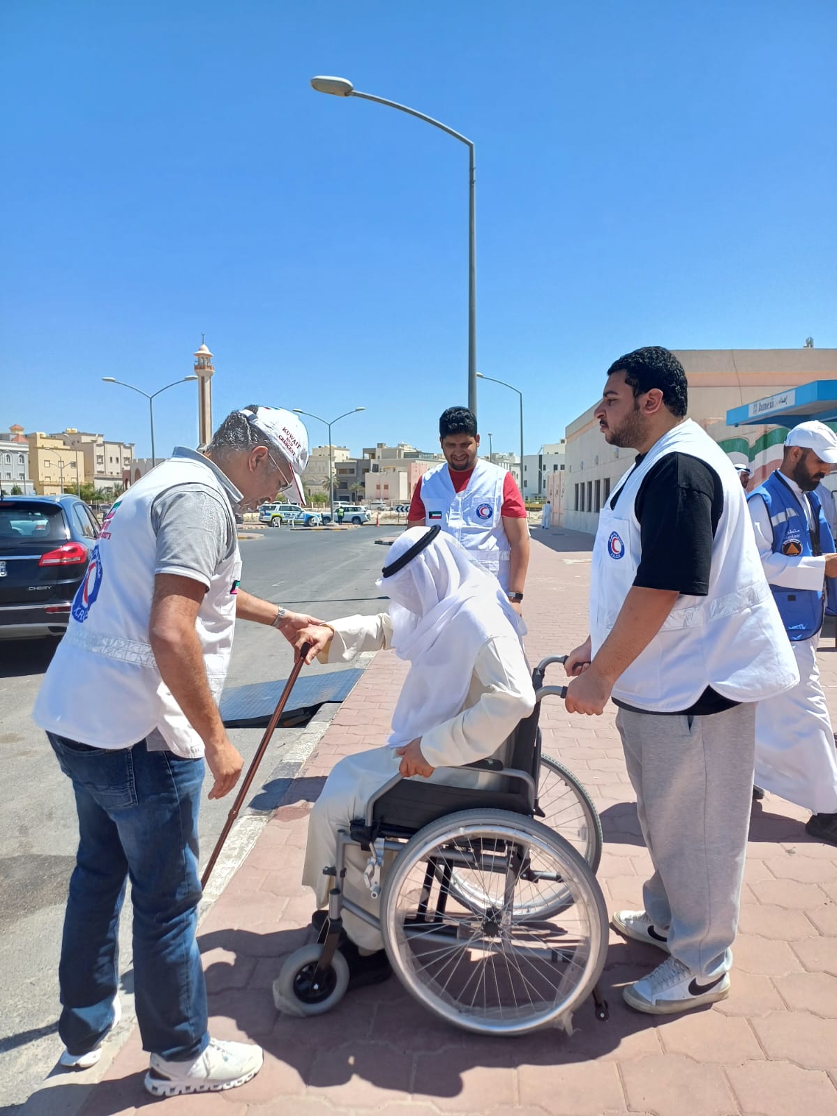 متطوعي من ( الهلال الاحمر الكويتي ) يساعد احد الناخبين	