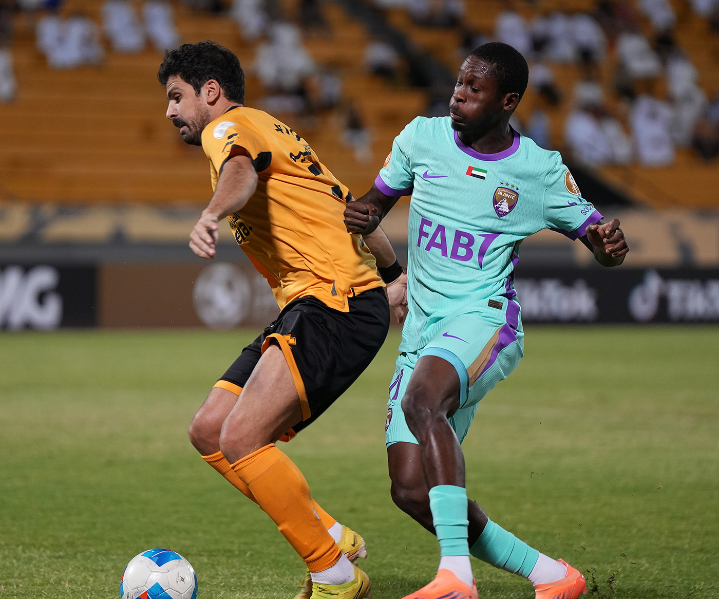 لاعب القادسية يحاول الاحتفاظ بالكرة وسط مضايقة من لاعب العين الاماراتي