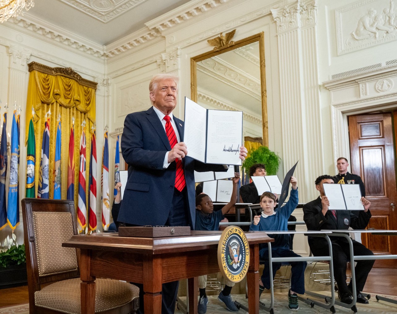 الرئيس الأمريكي دونالد ترامب يحمل الأمر التنفيذي بعد توقيعه