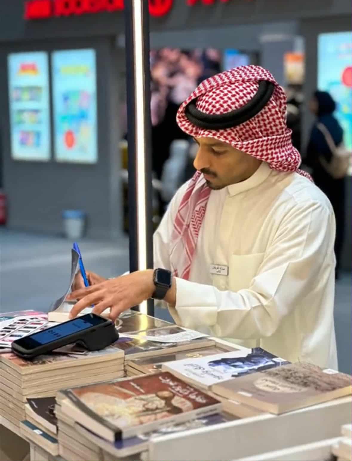 الكاتب مبارك العريفان أثناء توقيعه كتابه لاحد القراء
