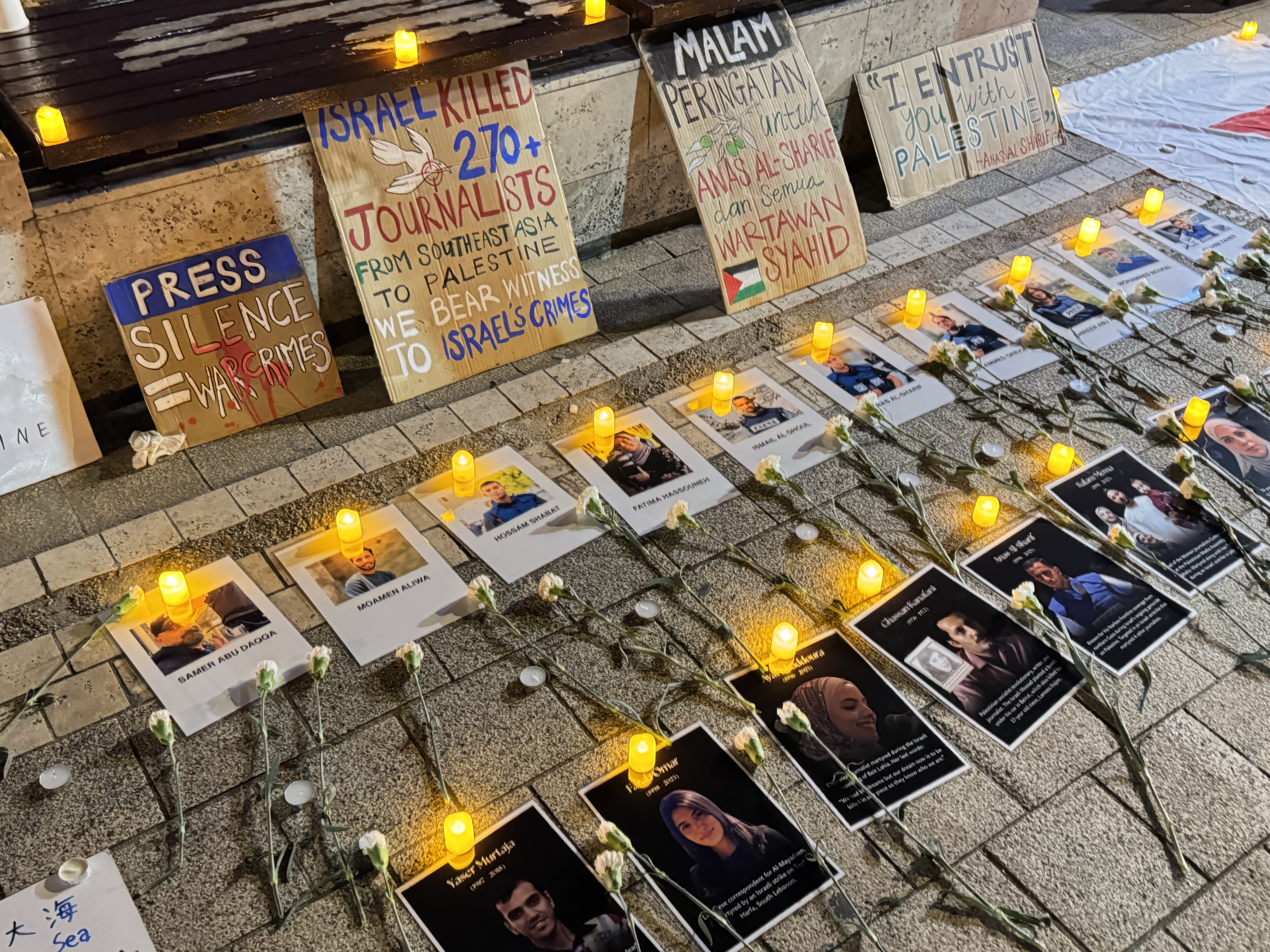 لوحات وشموع مضاءة أمام صور عشرات الصحفيين الفلسطينيين لتوثيق جرائم الاحتلال وإحياء ذاكرتهم في قلب كوالالمبور