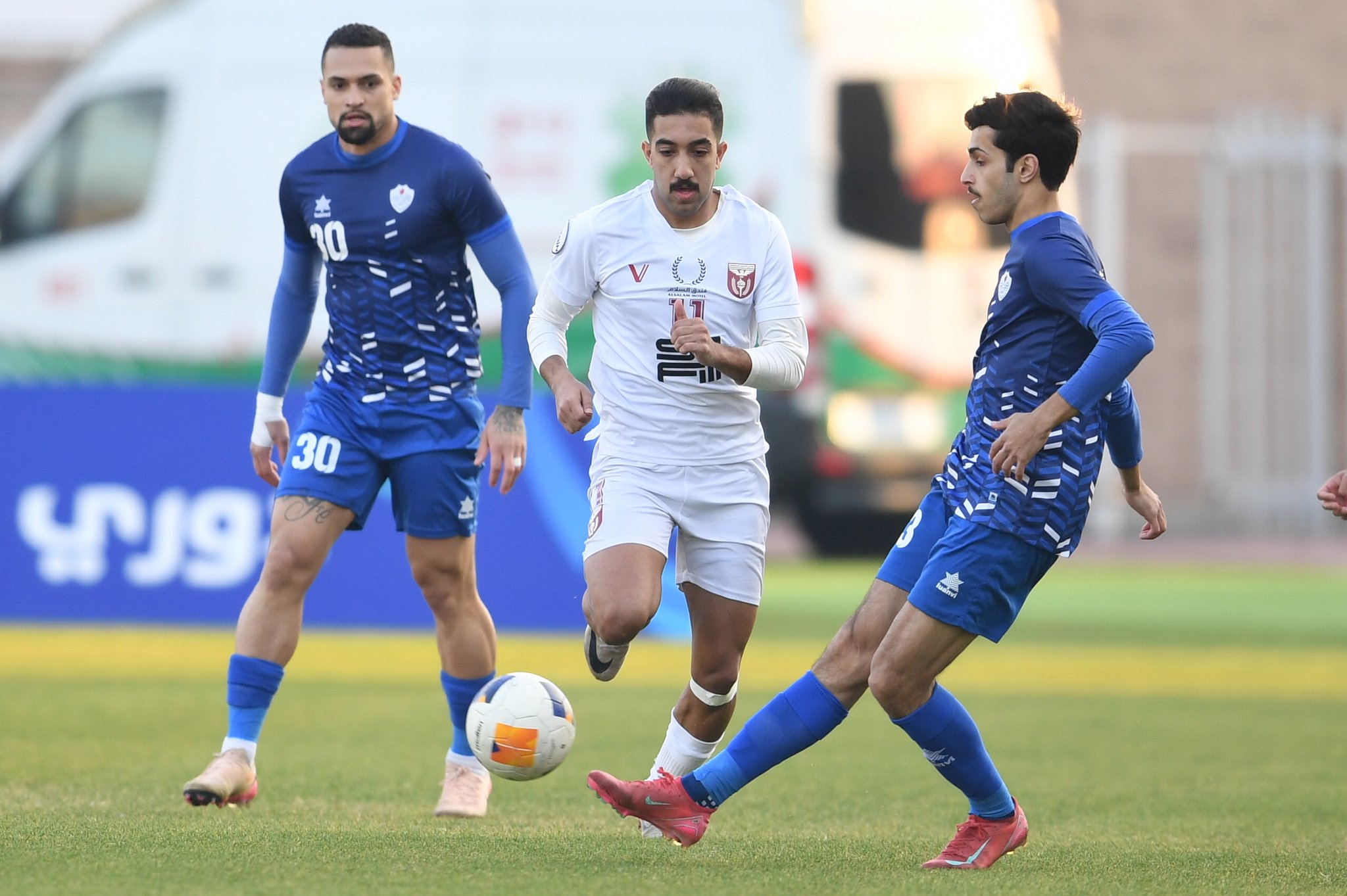 لاعب الشباب يمرر الكرة وسط مراقبة من لاعب النصر