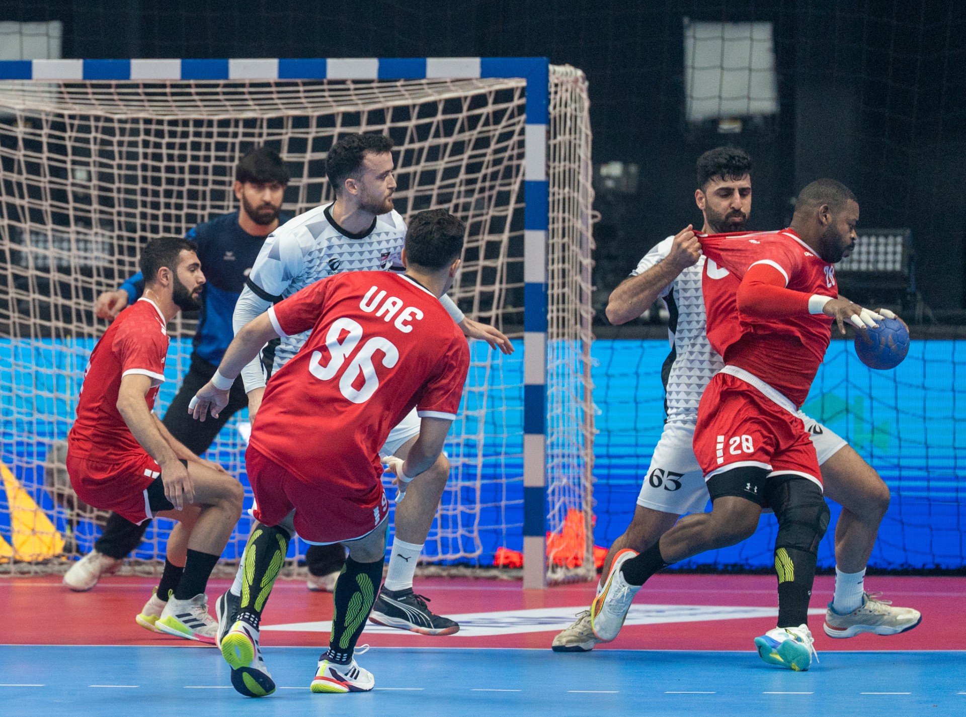 لاعب الامارات يحاول التصويب وسط مضايقة من لاعب العراق